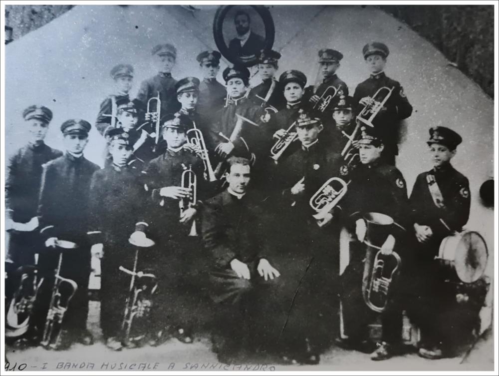 <div class="ql-editor"><div>Fotografia del 1910 che ritrae il maestro Don Matteo Pertosa con alcuni allievi della classe di ottoni della banda musicale. L’immagine documenta l’attività di formazione musicale svolta dalla banda a circa un decennio dalla sua fondazione.</div><div><br></div><div>La Banda Musicale di San Nicandro Garganico, fondata nel 1900 dal dott. Vincenzo Zaccagnino con finalità educative e sociali, rappresenta una delle espressioni della tradizione musicale della comunità. Nata con l’obiettivo di offrire ai giovani, in particolare a quelli provenienti da contesti svantaggiati, un’opportunità di formazione attraverso la musica, ha svolto nel tempo una funzione culturale e aggregativa nel territorio.</div><div>...