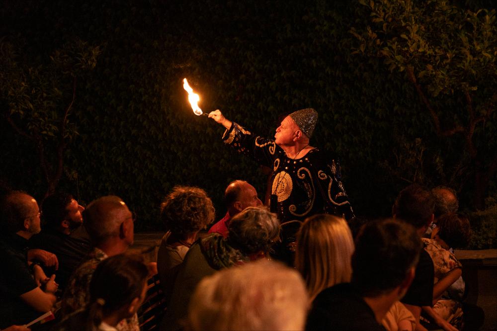 <div>La foto ritrae <strong>Leo Bassi</strong> nello spettacolo "<em>70 anni"</em>, presentato all’aperto nell’<strong>Ortale dei Cantieri Teatrali Koreja</strong> durante il <em>Teatro dei Luoghi – Festival internazionale</em>. Nel gesto spettacolare di sputare fuoco, l’artista porta in scena un racconto autobiografico che attraversa una vita intera dedicata all’arte del clown, alla provocazione e al gioco teatrale. Lo spettacolo, creato per i suoi settant’anni, intreccia ironia, memoria e vitalità, inserendosi nel cartellone dedicato al tema <em>Nessuna terra in vista</em>.</div>...