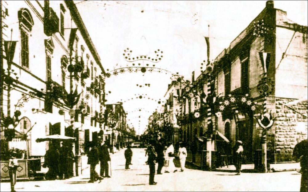 <div class="ql-editor"><div>La foto storica digitalizzata, databile al 1910, è testimonianza del suggestivo allestimento con le luminarie delle strade cittadine di Trani in occasione dei festeggiamenti organizzati per il Santo Patrono, San Nicola Pellegrino.</div><div>I festeggiamenti in onore di San Nicola il Pellegrino, Patrono di Trani, morto in città nel 1094, costituiscono uno degli appuntamenti più importanti della tradizione religiosa e civile tranese.</div><div>La festa patronale si svolge ogni anno nei giorni di sabato, domenica e lunedì della prima settimana di agosto ed è articolata in tre momenti principali.</div><div>Il sabato sera l’effigie lignea del Santo, custodita presso il Santuario di Santa Maria di Colonna, viene trasp...