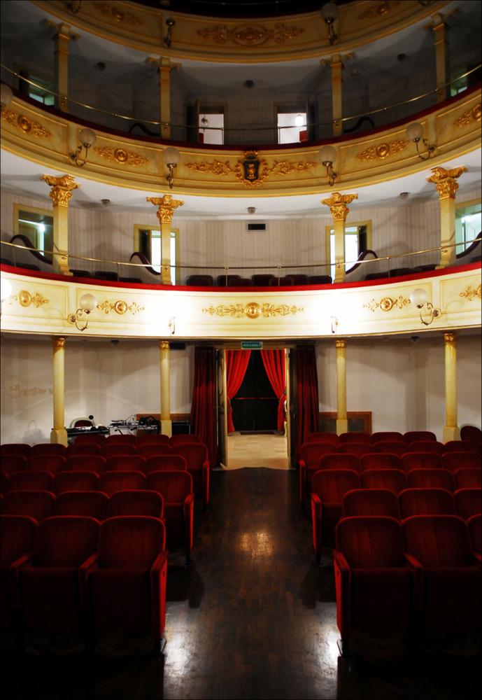 L'immagine è parte della campagna fotografica realizzata dalla fotografa Margherita Mirabella per Teatro Pubblico Pugliese, che ha ripreso nei suoi scatti le eleganti architetture e i rifiniti dettagli di alcuni dei più bei teatri pugliesi e alcuni degli spettacoli teatrali portati in scena in questi ultimi anni. È stata scattata all'interno del piccolo ed elegante Teatro Comunale di Mola di Bari, intitolato al suo più celebre cittadino, il compositore Niccolò Van Westerhout. Iniziati nel 1888 per volere dell'Amministrazione comunale, i lavori per la sua edificazione si conclusero nel 1896; il teatro era pronto così ad ospitare sul suo palco il 18 aprile l'opera “Doña Flor” che Van Westerhout dedicò a Mola, la sua città nativa. Il progetto originario dell'Ing. Vittorio ...