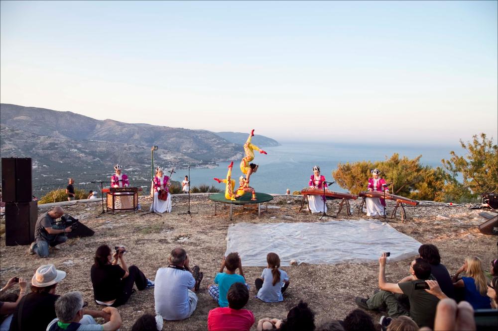 La fotografia è parte della collezione digitale “Puglia Green Hour” nata dall'omonimo progetto di Teatro Pubblico Pugliese. Fu organizzato su un calendario fitto e intenso di spettacoli programmati tra giugno e luglio 2012 all'interno dei Parchi Regionali della Puglia, per parlare di arte, musica, teatro e filosofia ispirati dalle bellezze primordiali del paesaggio pugliese in aree territoriali spesso dimenticate o poco valorizzate. L'immagine cattura un momento della suggestiva performance delle “Hulan”, gruppo al femminile proveniente dalla Mongolia, formato da 8 artiste tra musiciste, contorsioniste, una cantante e una ballerina. La performance di Hulan si è svolta nell'Area archeologica di Monte Saraceno, nella straordinaria scenografia naturale che si apriva sul ma...