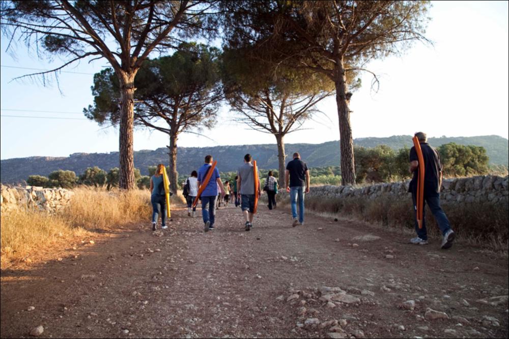 L'immagine digitale in oggetto è parte della collezione digitale “Puglia Green Hour”, che nasce dall'omonimo progetto di Teatro Pubblico Pugliese, organizzato su un calendario fitto e intenso di spettacoli programmati tra giugno e luglio 2012 all'interno dei Parchi Regionali della Puglia, per parlare di arte, musica, teatro e filosofia ispirati dalle bellezze primordiali del paesaggio pugliese in aree territoriali spesso dimenticate o poco valorizzate. La fotografia, scattata il 23 giugno del 2012 documenta la passeggiata organizzata all'interno del Parco Naturale Regionale Dune Costiere da Torre Canne a Torre San Leonardo, area di 1.100 ettari tra Ostuni e Fasano. La fitta vegetazione che si scorge in secondo piano, le folti chiome degli ulivi secolari, l'inconfondibil...