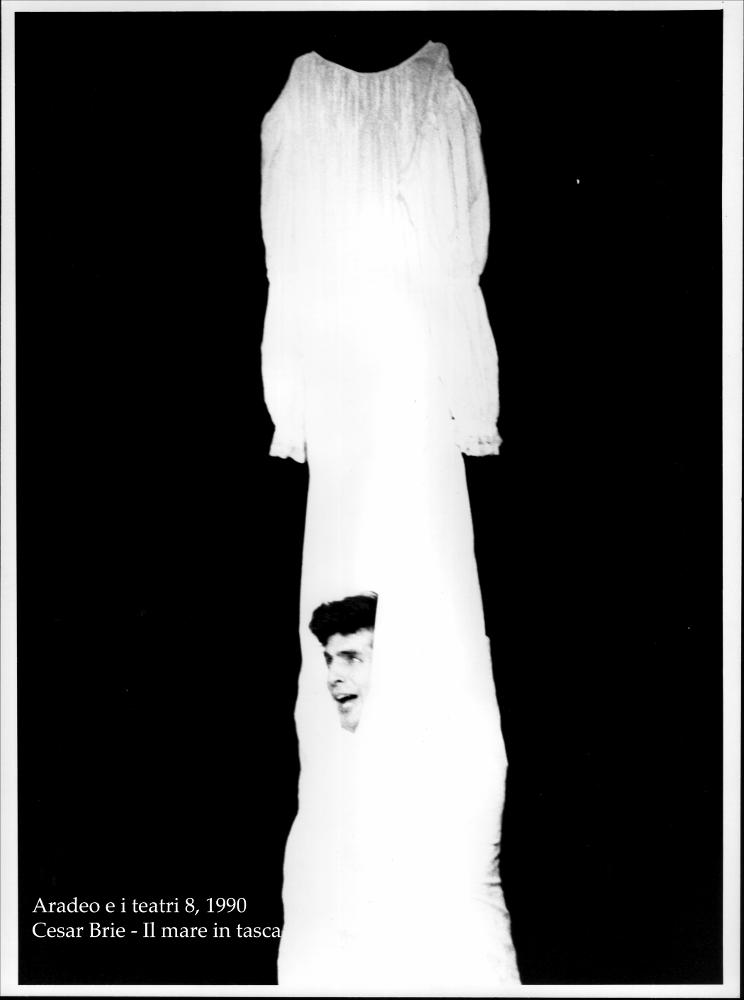 La fotografia in bianco e nero cattura un momento intenso della rappresentazione teatrale “Il mare in tasca”, messa in scena nel 1990 dal Teatro Koreja, nell'ambito della rassegna annuale “Aradeo e i Teatri”, un appuntamento con il teatro sperimentale che la compagnia nata nel 1983 nel piccolo borgo salentino di Aradeo porta avanti sin dall'anno della sua fondazione. Rappresentato e replicato durante l'ottava edizione della più importante kermesse culturale e teatrale della Puglia dell'epoca, lo spettacolo fu prodotto dalla compagnia Koreja, insieme con l'autore e attore teatrale argentino César Brie, che lo scrisse ed interpretò. Tutto si svolge in una stanza dietro la sagrestia di una chiesa, in un monologo che ha come tema l'amore, vissuto sotto diverse forme. La tra...