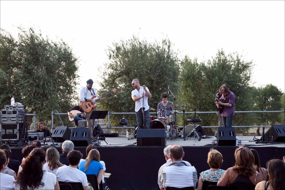 L'immagine digitale in oggetto è parte della collezione “Puglia Green Hour” nata dall'omonimo progetto di Teatro Pubblico Pugliese. Fu organizzato su un calendario fitto e intenso di spettacoli programmati tra giugno e luglio 2012 all'interno dei Parchi Regionali della Puglia, per parlare di arte, musica, teatro e filosofia ispirati dalle bellezze primordiali del paesaggio pugliese in aree territoriali spesso dimenticate o poco valorizzate. La fotografia riprende un momento dello spettacolo tenutosi nel Parco archeologico di San Leucio, nell'area di Canosa di Puglia; sul palco, al centro si nota il cantante italiano Gennaro Della Volpe, in arte Raiz, con il gruppo Radicanto. La collaborazione tra i due nasce dalla passione comune per la musica mediterranea e dal desider...
