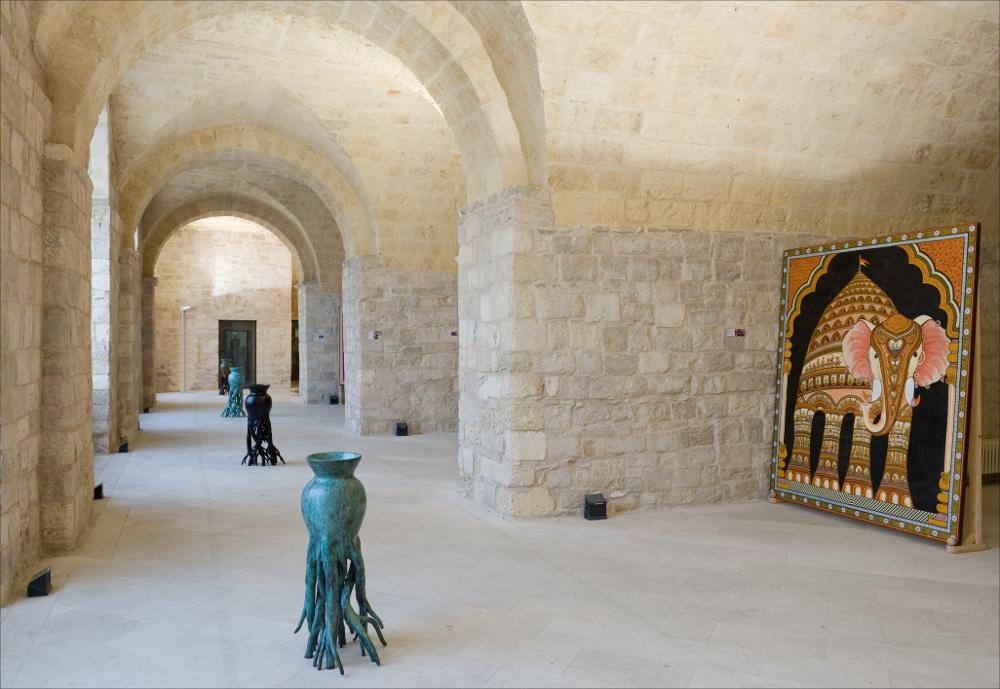 L'immagine digitale in oggetto, scattata in occasione della mostra “Le culture sacre dell'Arte” dell'artista pugliese Tarshito, realizzata dal 23 novembre 2008 al 25 gennaio 2009 negli spazi del Castello di Trani, gode di una buona luce naturale. Protagoniste dello scatto sono quattro vasi in bronzo dalla forma denominati dall'artista "Vasi con Radici" e realizzati nel 2004. All'arte scultorea di Tarshito va riconosciuta una grande forza comunicativa, gli stessi vasi sono pregni di un forte significato intrinseco che l'artista stesso non esita a svelare. Il vuoto all'interno delle anfore è un vuoto mistico, prezioso e misterioso che si apre all'ospitalità, tema quest'ultimo caro all'artista. Il vaso, dunque, è l'archetipo del vivente-ospitale, contenitore e conservatore...