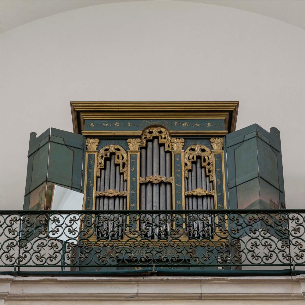 L'organo rappresentato nell'immagine digitale è collocato nella chiesa madre di Santa Maria delle Grazie di Merine, frazione di Lizzanello (Le). La chiesa risale al 1641 ma venne completamente ricostruita nell’Ottocento dall’architetto G. Maiola. Il profilo in pietra leccese appare molto semplice con il tradizionale timpano triangolare e la presenza della torre dell’orologio. L’interno a croce latina presenta sei cappelle e sull’altare maggiore in pietra una tela della Madonna delle Grazie. Tra gli arredi lignei si annoverano il maestoso tabernacolo e l’organo. Collocato in una cantoria in controfacciata, è una cassa con profilo piatto suddiviso da quattro pilastrini che terminano con un capitello composito dorato stilizzato con motivi floreali. L’organo è decorato nell...