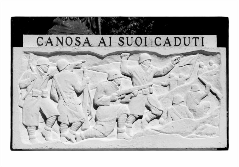 L'immagine digitale mostra un particolare del Monumento ai Caduti a Canosa di Puglia. Nello specifico si tratta del basamento istoriato con scene di fanti immortalati in combattimento, durante l'attacco. È possibile risalire all'iter che ha portato alla costruzione del monumento partendo dalla lettura del carteggio custodito presso l'Archivio Storico Comunale di Canosa di Puglia. Rispondendo ad un bando pubblico emanato dal Comune di Canosa sulla "Gazzetta di Puglia", Francesco Pinto si propone come scultore per la realizzazione del monumento. In una lettera, datata 4 settembre 1924, dichiara di essere disposto a "recarsi sul posto, anche per rendersi conto dell'ubicazione del monumento da erigere essendo molto utile la conoscenza della località prima di approntare un b...