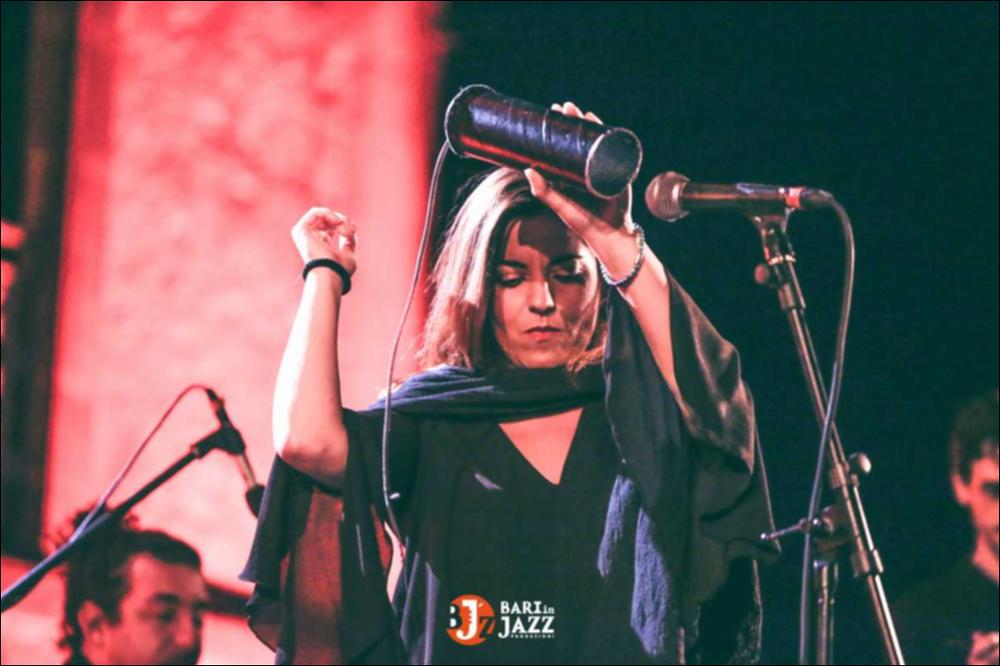 "Bari in Jazz" è un Festival Metropolitano con cadenza annuale, organizzato da Abusuan in Puglia, presenta concerti con ospiti nazionali ed internazionali. L’edizione 2018 del Festival Metropolitano "Bari in Jazz", la quattordicesima, è stata interamente dedicata alle figure femminili nella musica e nel jazz, nel canto, nella composizione e nell’arrangiamento, nell’uso dei vari strumenti e stili musicali. Come ogni anno il Festival Metropolitano Bari in Jazz, luogo d’incontro della musica jazz con altri generi musicali, offre una vetrina d’eccellenza alle grandi artiste e a quelle emergenti, promuovendo anche nuove creazioni. La fotografia mostra la cantante, al centro, mentre suona una maracas autocostruita....