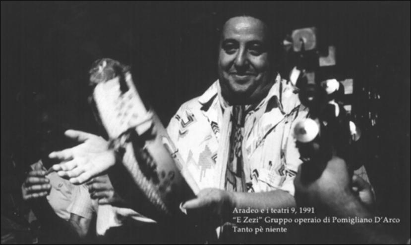 La fotografia in bianco e nero è un momento dello spettacolo "Tanto pè niente", interpretato nel 1991 da "E Zezi - Gruppo operaio di Pomigliano D'Arco" durante la nona edizione di "Aradeo e i Teatri", un appuntamento con il teatro sperimentale che la compagnia Koreja nata nel 1983 nel piccolo borgo salentino di Aradeo portò avanti sin dall'anno della sua fondazione. Quello di "E Zezi" è un gruppo storico di musica popolare napoletana e campana nato negli anni '70 del Novecento per volontà di un gruppo di operai, artigiani e studenti che si fecero interpreti della classe operaia e di un Sud anti-borghese legato alle tradizioni più autentiche, lontane dalla omologazione culturale. La loro unicità consiste anche nell'estendere il repertorio musicale alle altre tradizioni m...