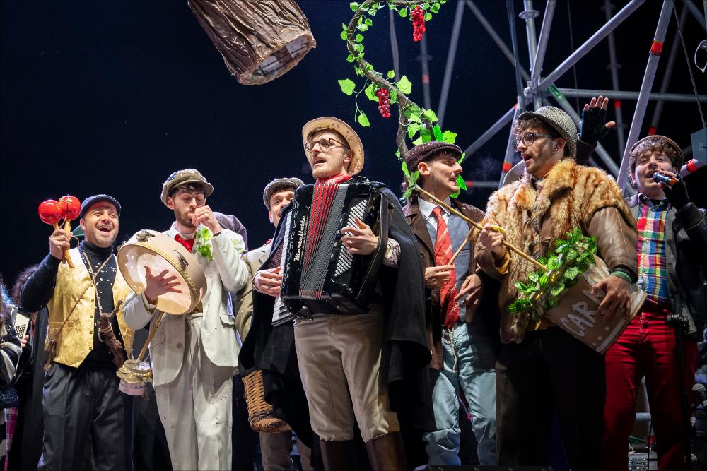 <p>La fotografia ritrae l’energia e l’ironia di “Le Propaggini”, il tradizionale festival in vernacolo che ha aperto la 630^ edizione del Carnevale di Putignano il 26 dicembre. Sul palco di Largo Porta Nuova, otto gruppi di poeti irridenti hanno animato il pubblico con rime pungenti e satira locale, celebrando l’antica tradizione contadina che da secoli anima la città. L’immagine cattura il momento in cui i propagginanti, tra costumi colorati e sorrisi contagiosi, portano avanti la festa che unisce storia, divertimento e spirito di comunità.</p>