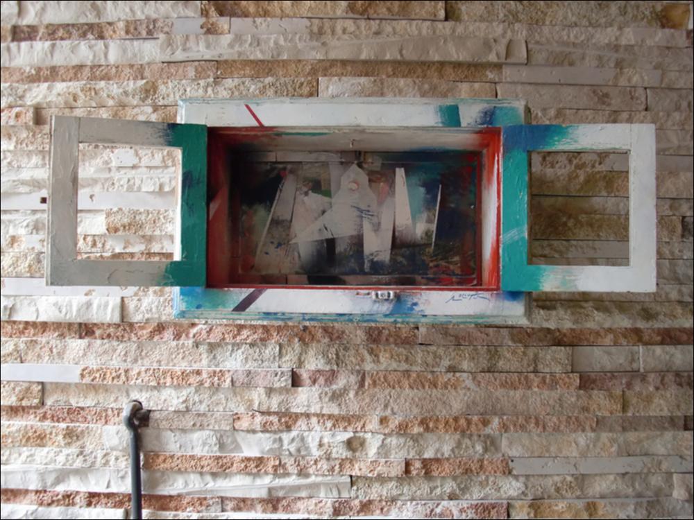 L'immagine digitale riproduce l'opera “Urbe dalla finestra”, dell'artista pugliese Michele Roccotelli. Classe 1946, iniziò i suoi studi a Bari per perfezionarli a Roma ed iniziare, giovanissimo nel 1968, a dedicarsi ad esposizioni, personali, rassegne nazionali prestigiose nel panorama artistico contemporaneo italiano dell'epoca (Arte Fiera di Bologna, Arte Roma e le Expo Arte baresi) e mostre internazionali persino in Canada e negli ultimi anni molte in Germania. L'artista, famoso per lo più per i suoi dipinti, racconta il territorio pugliese anche attraverso sculture di riuso. Finestre e piccoli oggetti d'arredo comuni prendono nuova forma grazie al suo personale uso dei colori. Anche in “Urbe dalla finestra” è evidente l'astrattismo tipico di Roccotelli: dalle ante d...