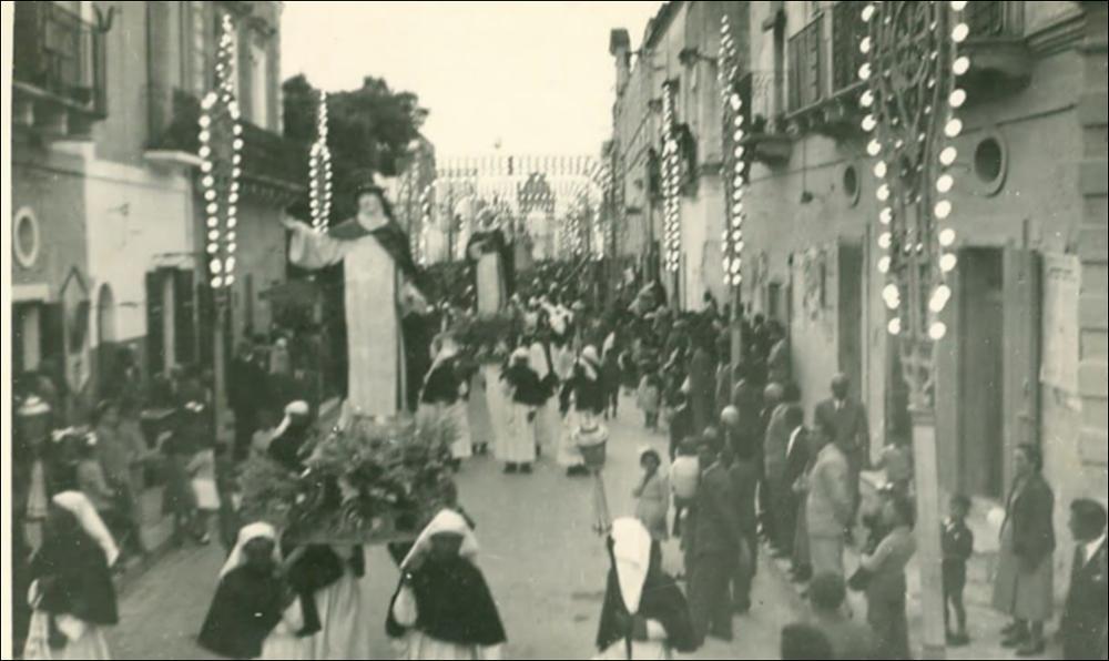 Negli anni ’50, una fotografia della festa patronale restituisce un’immagine più nitida e partecipata del corteo processionale: le strade del paese sono gremite, le case addobbate con drappi e coperte ai balconi, e al centro della scena avanzano i tre simulacri portati a spalla dai devoti: Santa Caterina da Siena, San Domenico di Guzmán e la Madonna del Rosario. <div><br>La Festa Patronale della Beata Vergine del Santissimo Rosario di Montemesola (TA) è uno degli appuntamenti più sentiti e identitari della comunità. La celebrazione prende avvio nel fine settimana più vicino al 22 agosto, anniversario dell’elevazione della Vergine a Patrona del paese (22 agosto 1872), e si conclude il 7 ottobre, giorno della festività liturgica della Madonna del Rosario.</br></div>
